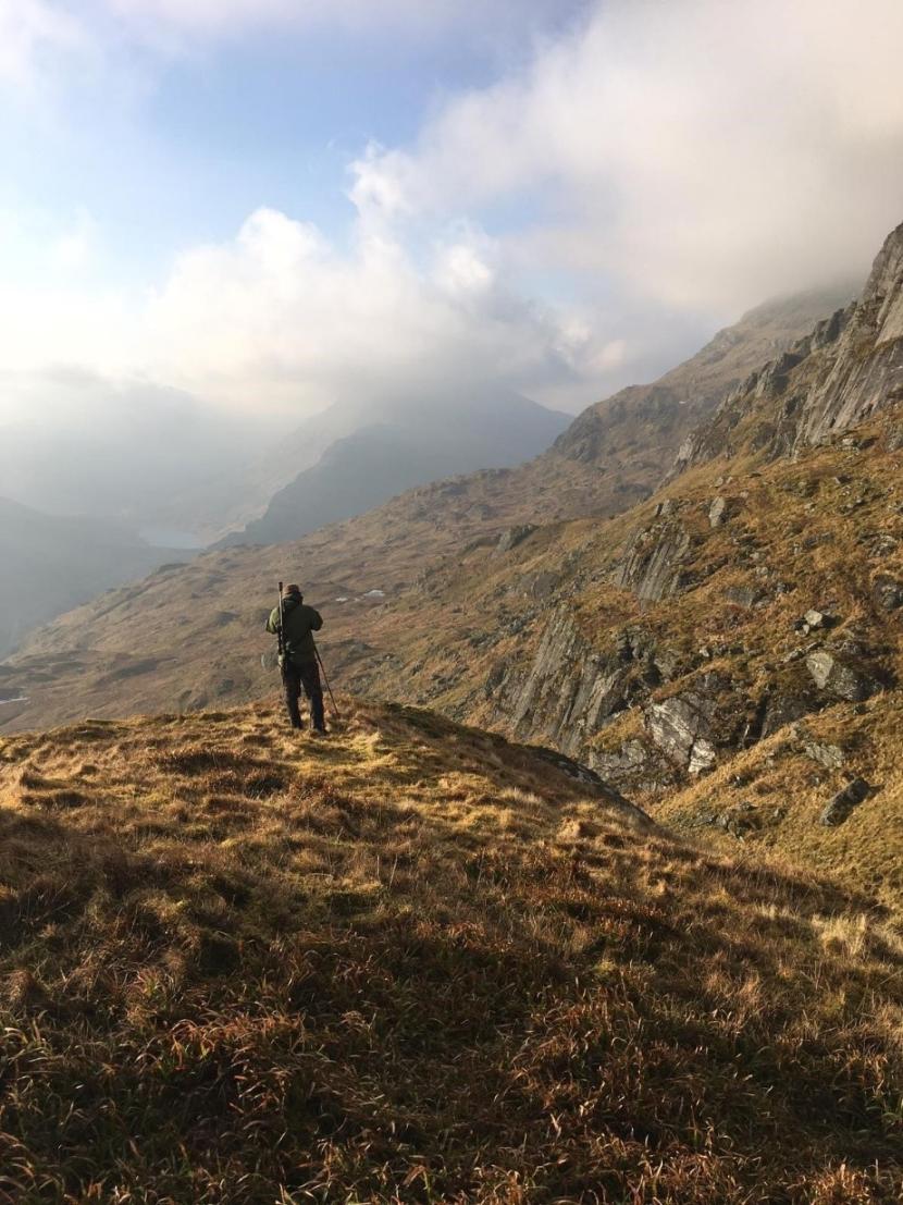 A person standing on a mountain, hind stalking.