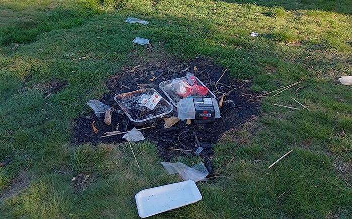 Disposable BBQ on ground with litter scattered nearby
