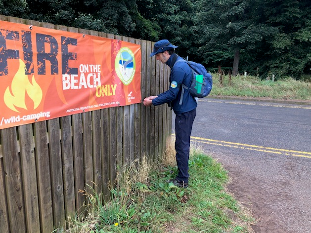Person attaching a banner to a fence
